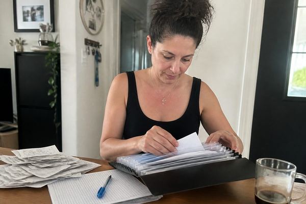 אדם בשנות ה-40 ליד שולחן מארגן קבלות ומסמכים בתוך תיקייה, ממוקד ורגוע, באור יום